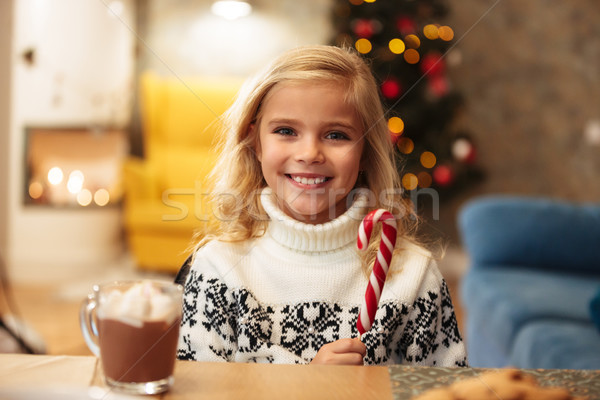Smiling little girl holding candy cane, looking at camera while  Stock photo © deandrobot