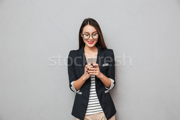 Souriant asian femme d'affaires lunettes écrit un message [[stock_photo]] © deandrobot