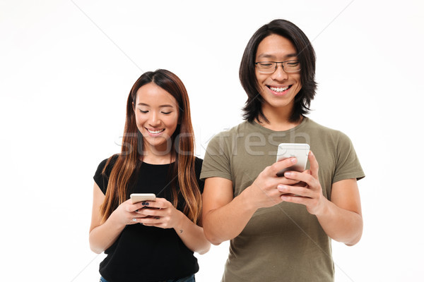 Stock photo: Portrait of a smiling young asian couple using mobile phones