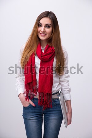 Stock photo: Portrait of a happy young woman with laptop over gray background