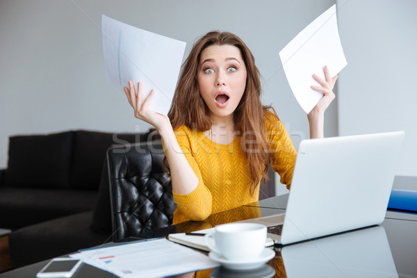 Amazed woman sitting at the table with bills Stock photo © deandrobot