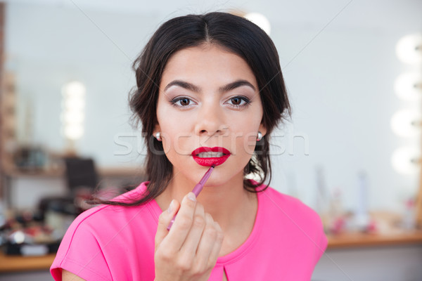 Tender attractive young woman putting on red lipstick Stock photo © deandrobot