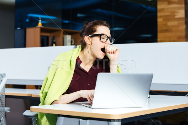 Pretty overworked businesswoman yawning and using laptop on workplace Stock photo © deandrobot