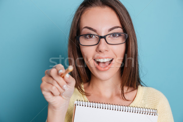 Stock photo: Close-up of a girl pointing at camera holding notebook