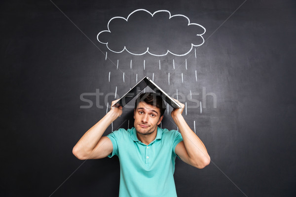 Stock photo: Man imitating roof with latop and covering from drawn rain