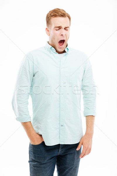 Tired exhausted young man standing and yawning Stock photo © deandrobot