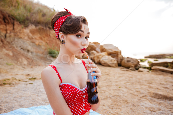 Young pin up woman drinking sweet drink from glass bottle Stock photo © deandrobot