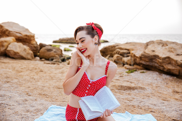 Stock photo: Pin up girl sitting with open book at the beach