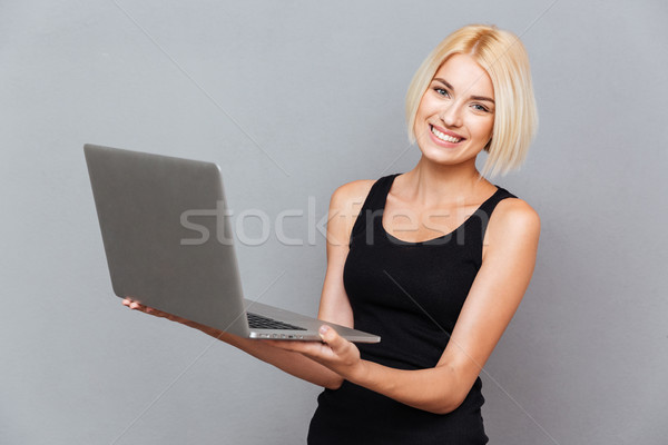 Retrato alegre encantador mulher jovem em pé usando laptop Foto stock © deandrobot