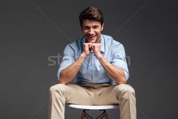 Smiling handsome man in blue shirt sitting on the chair Stock photo © deandrobot