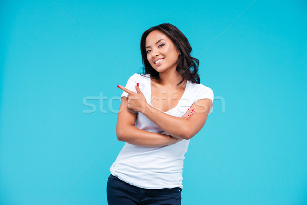 Cheerful young vietnamese girl pointing finger away at copyspace Stock photo © deandrobot