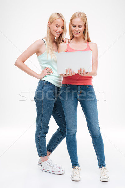 Young women dressed in t-shirts and jeans holding laptop Stock photo © deandrobot