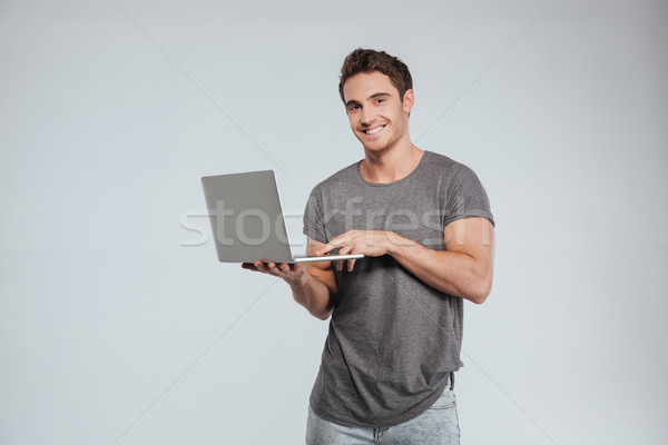 Happy smiling man using laptop and looking at camera Stock photo © deandrobot