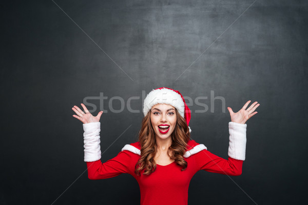 Mulher vermelho papai noel posando as mãos levantadas feliz Foto stock © deandrobot