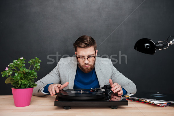 Handsome young businessman sitting at the table and using turntable Stock photo © deandrobot