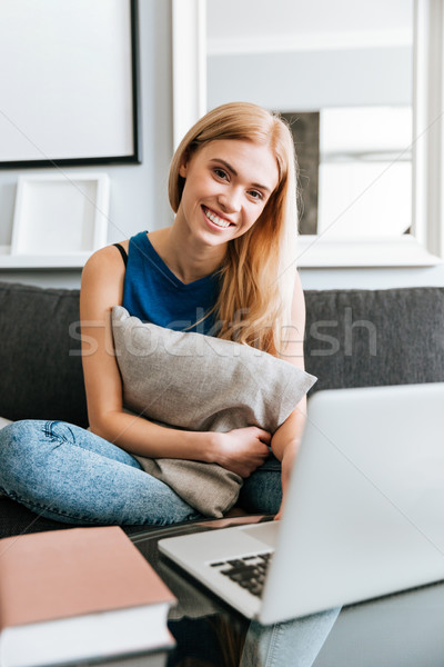 Alegre mujer almohada usando la computadora portátil sofá Foto stock © deandrobot