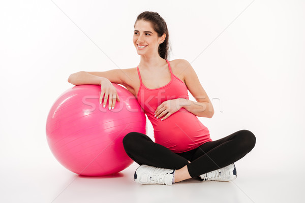 Beautiful young pregnant woman sitting with fitball and looking away Stock photo © deandrobot