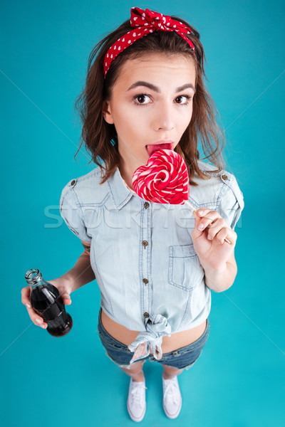 Young lady eating candy and holding aerated sweet water. Stock photo © deandrobot