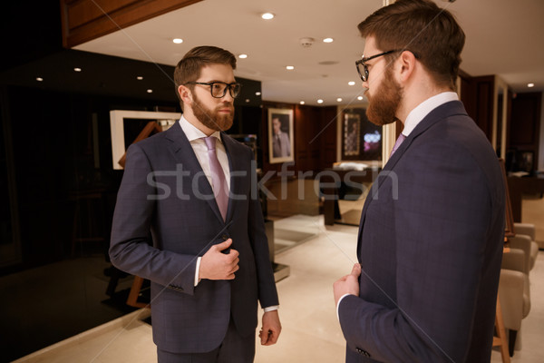 Concentrated young bearded businessman standing indoors Stock photo © deandrobot