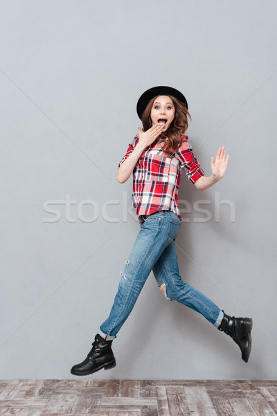 Portrait of an excited young woman in plaid shirt jumping Stock photo © deandrobot
