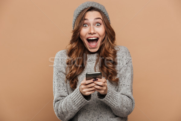 Happy exited pretty girl in gray knitted hat and warm sweater ho Stock photo © deandrobot