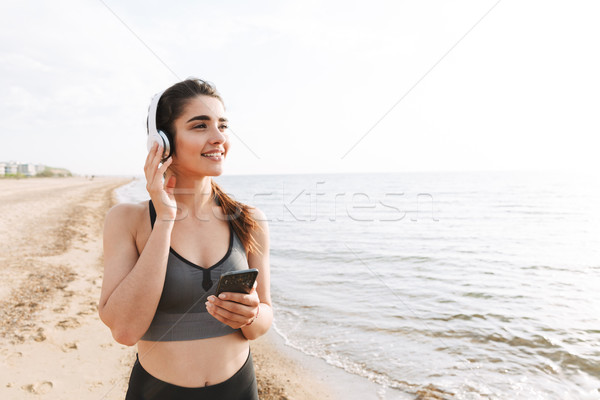 Szczęśliwy młodych sportsmenka uruchomiony plaży słuchanie muzyki Zdjęcia stock © deandrobot