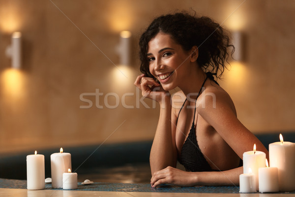 Cheerful happy beautiful woman in spa lies resting with candles. Stock photo © deandrobot