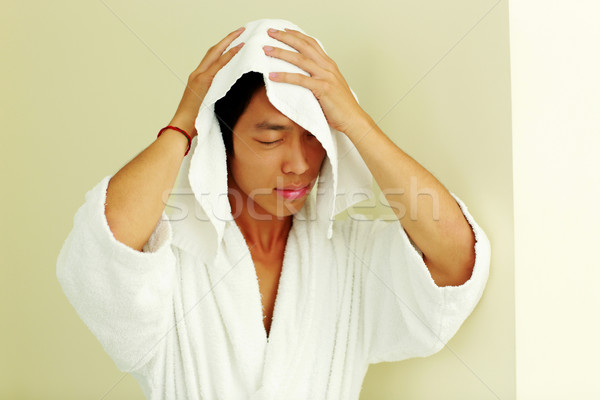 Asian man in bathrobe wiping face with a towel Stock photo © deandrobot