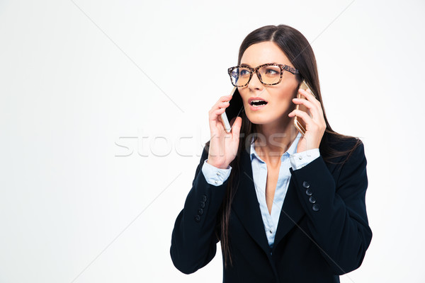 Businesswoman talking on two phones Stock photo © deandrobot