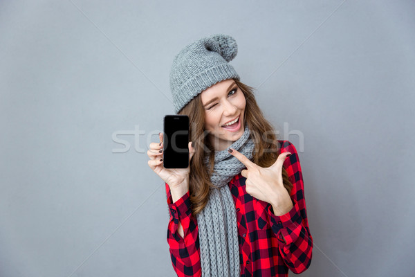 Woman winking and pointing finger on blank smartphone screen Stock photo © deandrobot