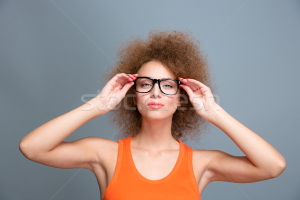 Confident young female with voluminous curly hairstyle in glasses Stock photo © deandrobot