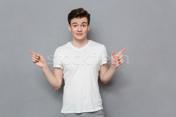 Verward jonge man tonen vingers verschillend Stockfoto © deandrobot