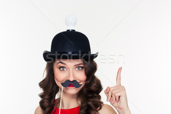 Girl in hat with light bulb using fake moustache props Stock photo © deandrobot