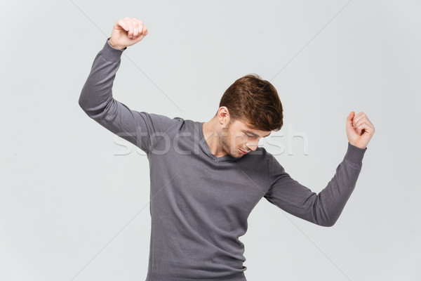 Attractive young man in grey pullover dancing Stock photo © deandrobot