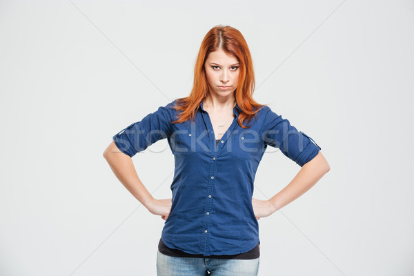 Angry irritated redhead young woman standing with hands on waist Stock photo © deandrobot
