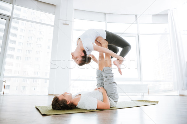 Peaceful couple doing acro yoga exercises in studio together Stock photo © deandrobot