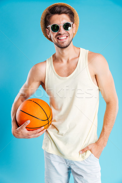 Cheerful young man in hat and sunglasses holding basketball ball Stock photo © deandrobot