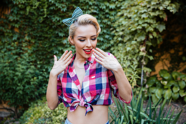 Smiling shy pin-up girl in plaid shirt and headband Stock photo © deandrobot