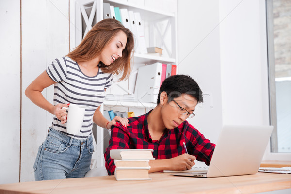 Stock photo: Female student communication with groupmate writing notes in notebook