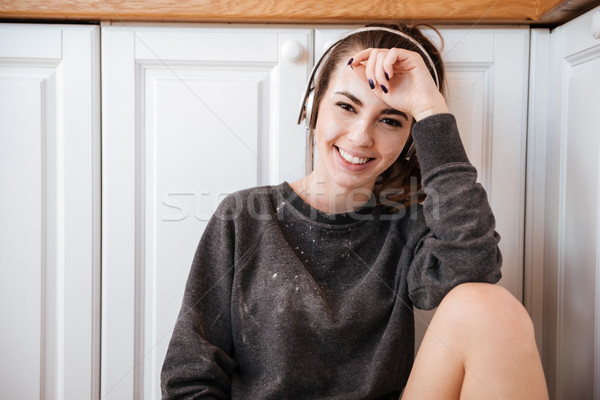 Woman listening to music with headphones in the kitchen Stock photo © deandrobot