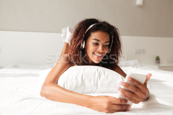 Pretty woman lying on pillow and listening music Stock photo © deandrobot