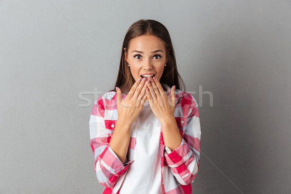 Portrait of young shocked brunette girl covering her mouth in su Stock photo © deandrobot