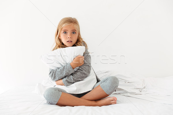 Portrait of a scared little girl hugging pillow Stock photo © deandrobot