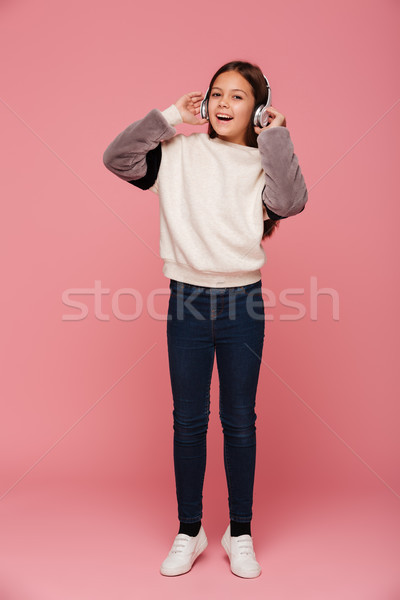 Cheerful girl using headphones and listening music isolated Stock photo © deandrobot