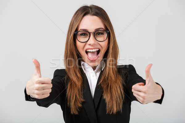 Happy cheerful lady showing thumbs up isolated over greywall Stock photo © deandrobot
