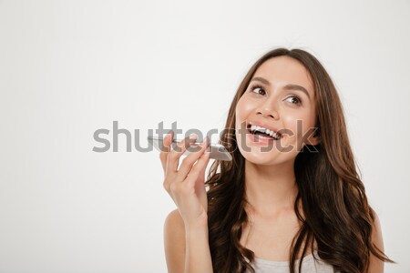 Portrait of happy woman with long brown hair talking into cellph Stock photo © deandrobot