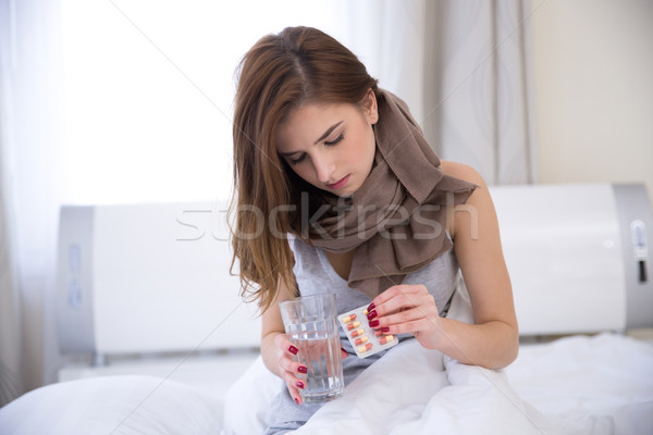 Genç kadın oturma yatak hapları cam su Stok fotoğraf © deandrobot