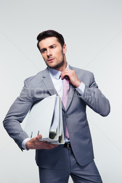 Jóképű üzletember nyakkendő tart mappák szürke Stock fotó © deandrobot