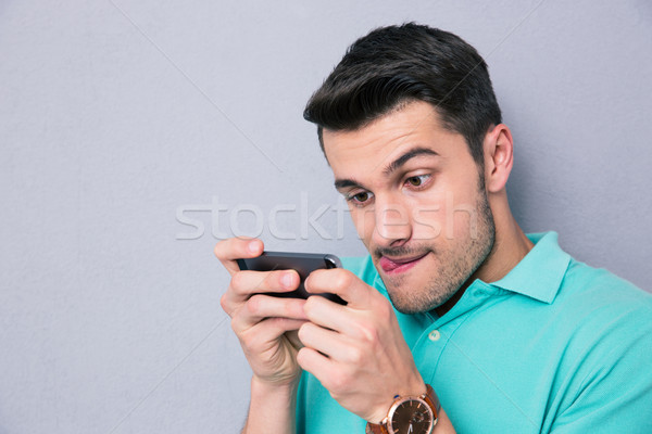 Funny man using smartphone over gray backgrpound Stock photo © deandrobot