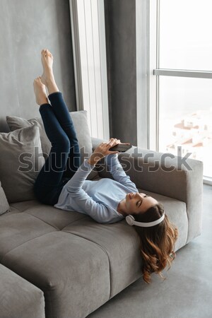 Happy attractive woman laying on the bed and taking off jeans Stock photo © deandrobot
